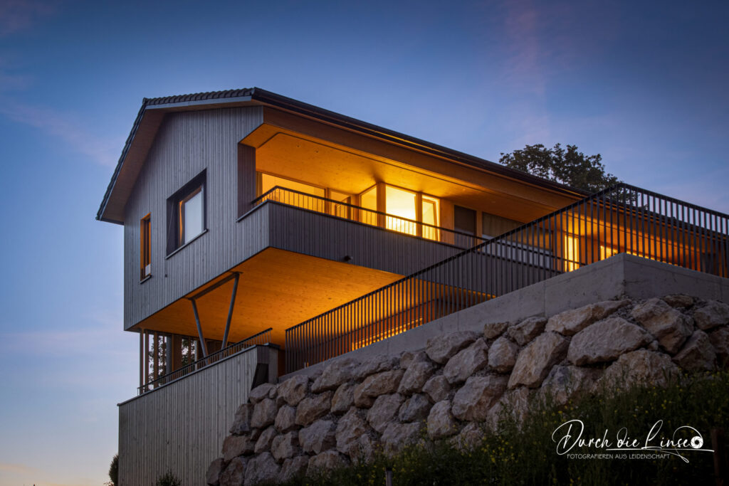modernes Wohnhaus in der Abendstimmung fotografiert, mit Lichtern innen