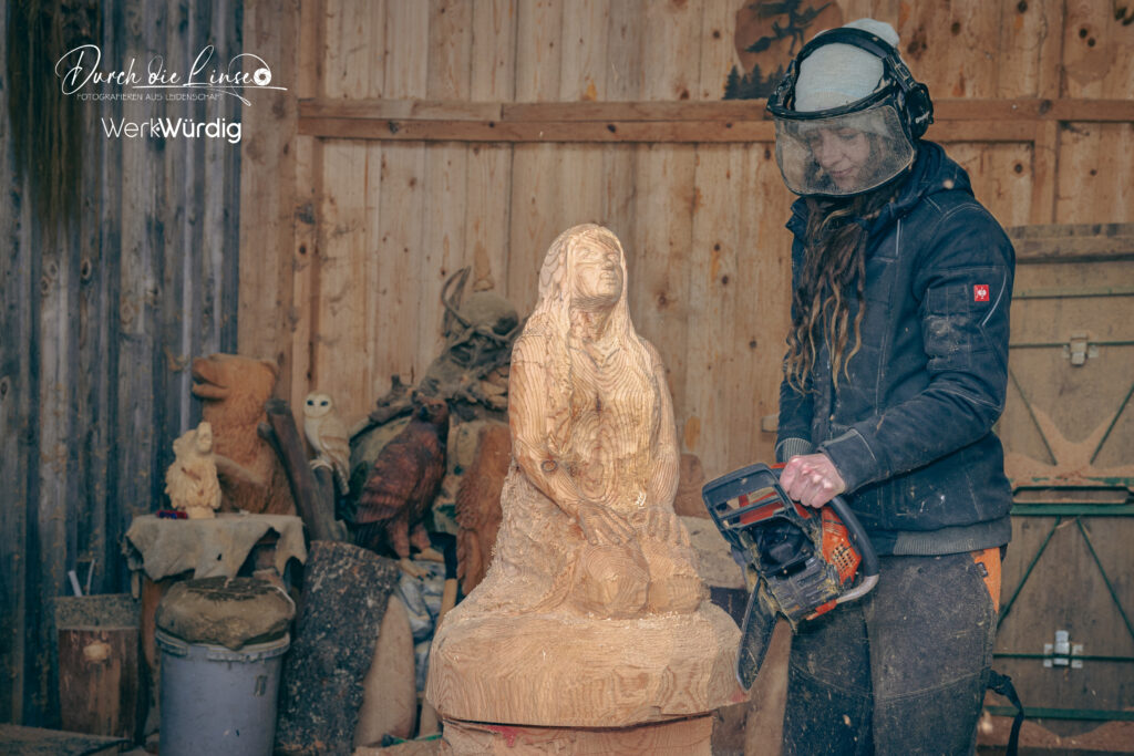 Holzkünstlerin Lisa Hirschbichler arbeitet mit der Motorsäge an einer Holzskulptur.