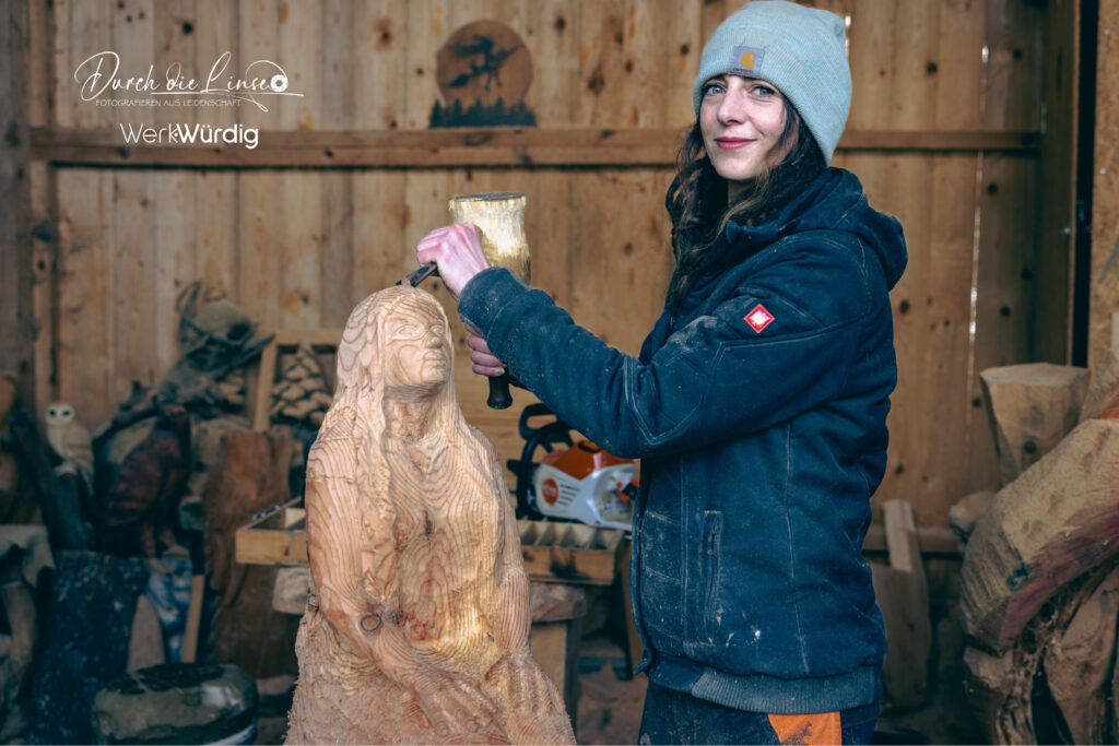 Holzkünstlerin Lisa Hirschbichler arbeitet mit dem Hammer an einer Holzskulptur.