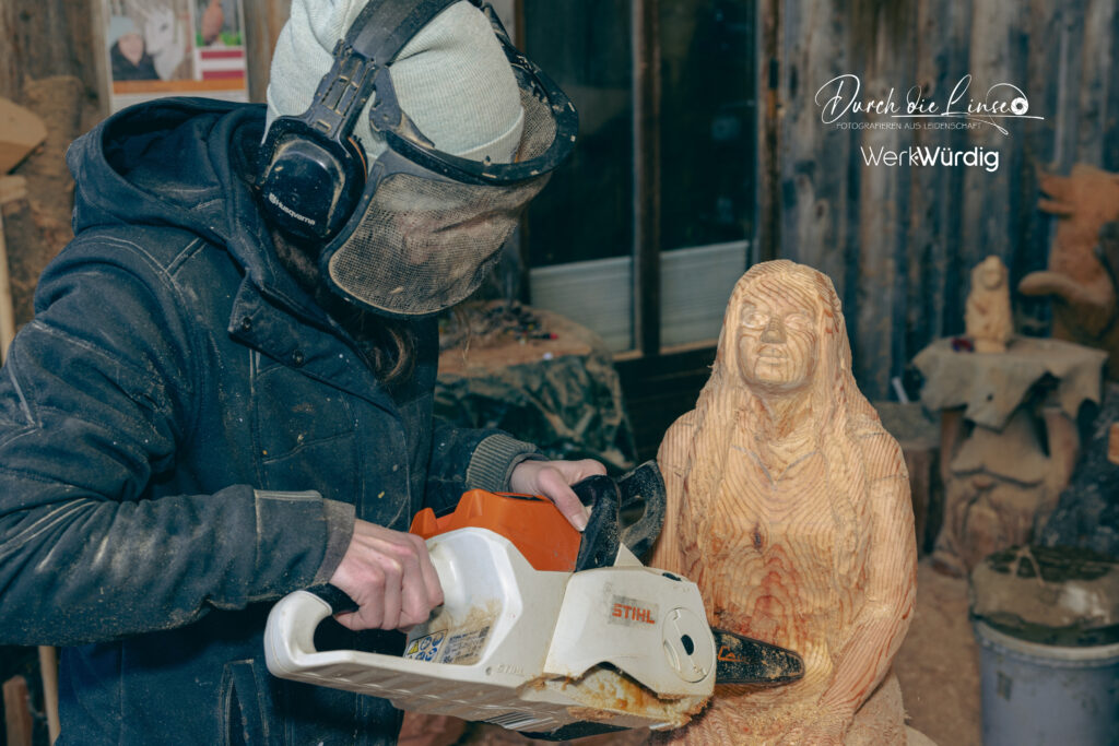 Holzkünstlerin Lisa Hirschbichler arbeitet mit der Motorsäge an einer Holzskulptur.