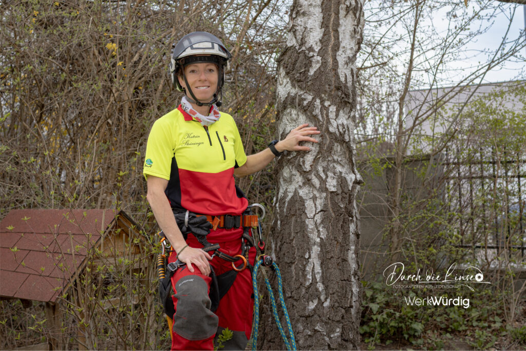 Baumpflegerin Katrin Steininger im Portrait bei einem Baum stehend.